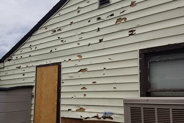 before photo of severe damamge of siding on home Advanced Exteriors Denver