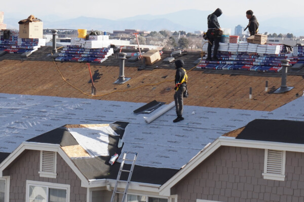 roofing crews work on installing new roof Advanced Exteriors Denver